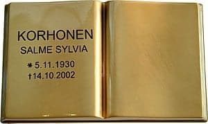 Kuvassa on Pronssikirja (muistolaatta kirja). Kirja on kullattu ja avonainen. Kirjan vasemmalla sivulla on teksti mustalla.